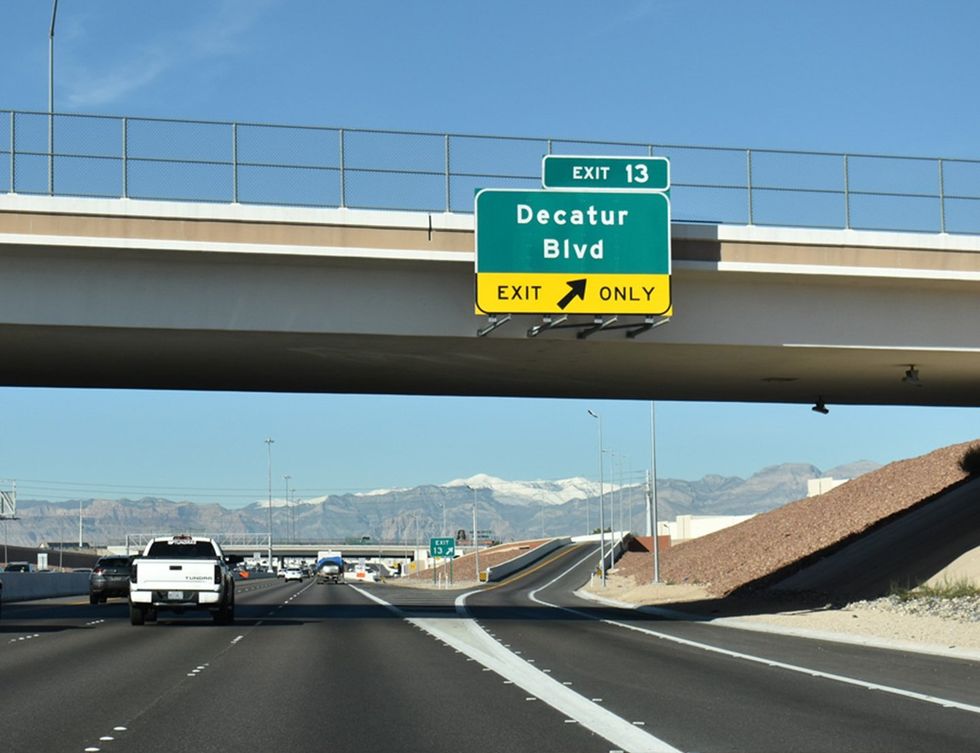 Highway overpass with a green Decatur Boulevard exit sign for Exit 13, traffic passing below.